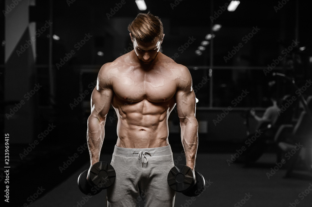 sexy strong bodybuilder athletic men pumping up muscles with dumbbells