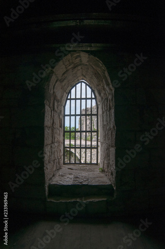 Ancient window with metal bars in a stone house. © Юрий Бартенев