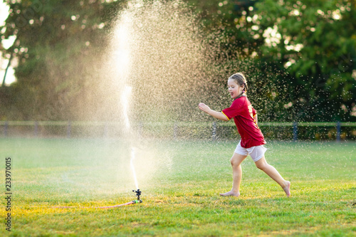 Kids play with water. Child with garden sprinkler.