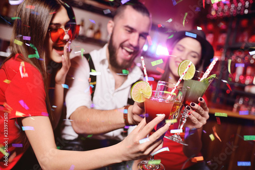 young people celebrate a birthday or Christmas on a nightclub background and salute their confetti