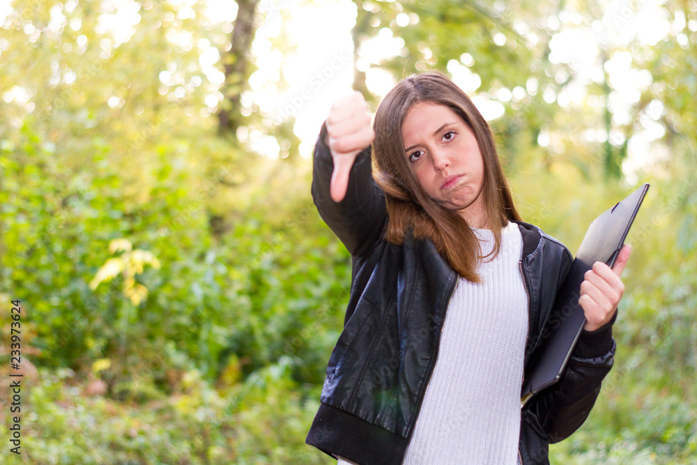 Woman or young european Caucasian college girl or sad student with folder and negative gesture with her hand has suspended all exams on the university campus Woman or young european Caucasian college girl or sad student with folder and negative gesture with her hand has suspended all exams on the university campus