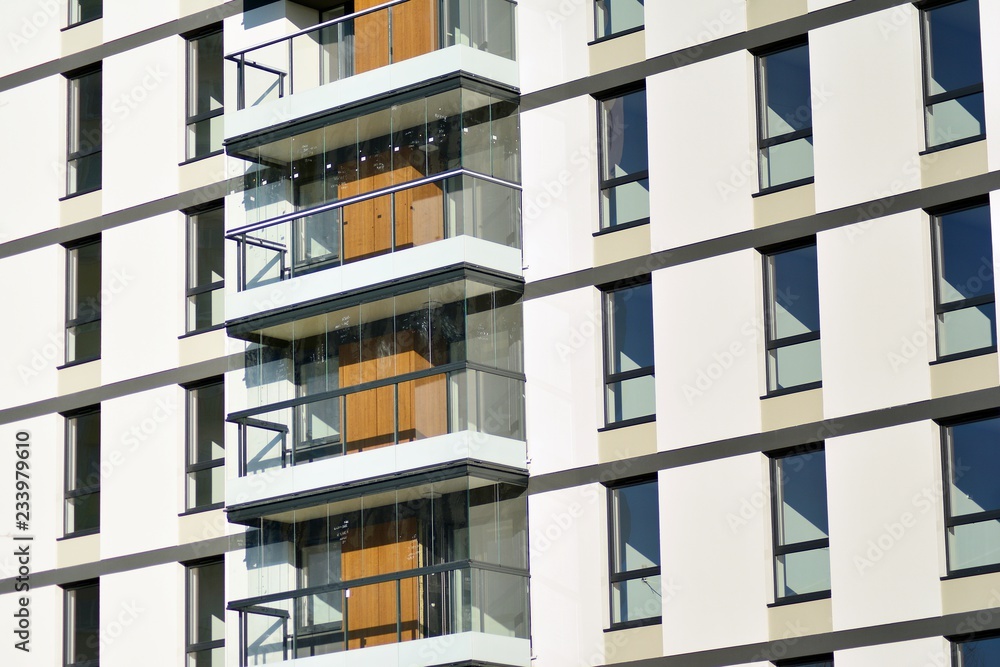 Fragment of a facade of a building with windows and balconies. Modern home with many flats. Fragment of a facade of a building with windows and balconies. Modern home with many flats.