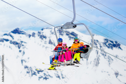 Family in ski lift in mountains. Skiing with kids