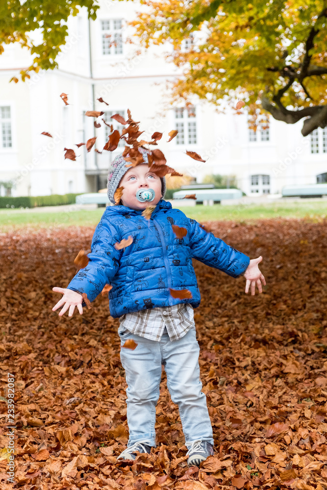 Kleiner Junge wirft Herbstflätter hoch Kleiner Junge wirft Herbstflätter hoch