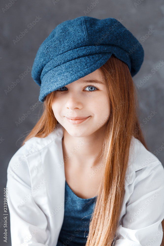 A beautiful girl wearing a dark blue hat. A girl in a studio sitting in the chair and smiling A beautiful girl wearing a dark blue hat. A girl in a studio sitting in the chair and smiling