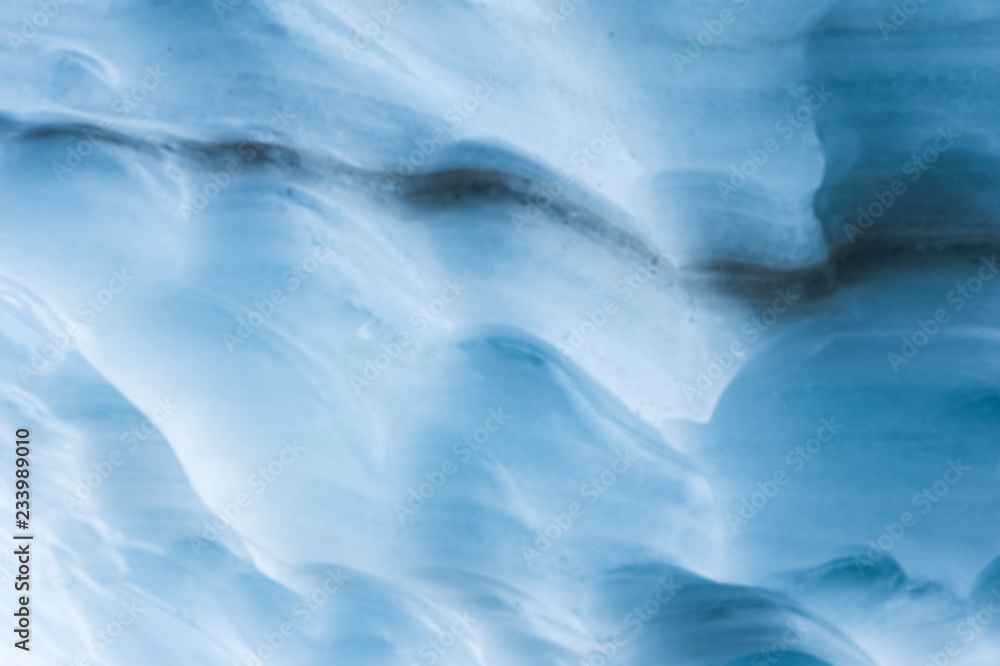 Obraz premium Close-up blurred wall of a centuries-old glacier with a structure of stripes and bubbles. Ice blue light texture