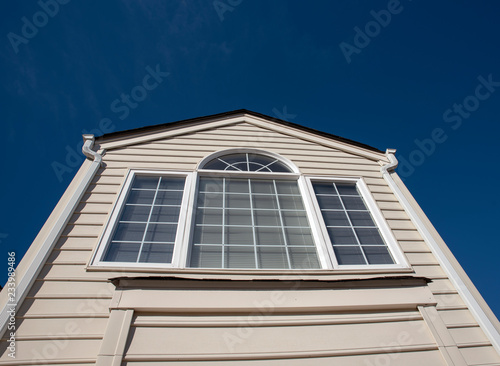 Side of a house showing windows and siding with blue sky background