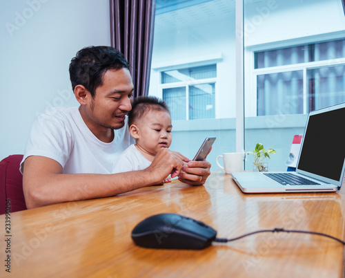 Man father working on laptop computer and using smartphone technology