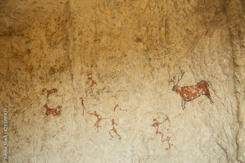 Rock paintings of hunters and wild animals in a cave