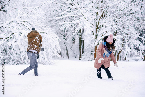 Loving young couple playing with snowballs in a winter park. Family love and care concept.