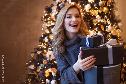 Beautiful young blonde with gift boxes under the Christmas tree