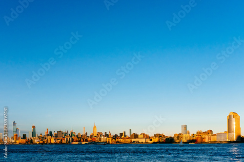 Skyline of midtown Manhattan over Hudson River under blue sky, at sunset, in New York City, USA © Mark Zhu