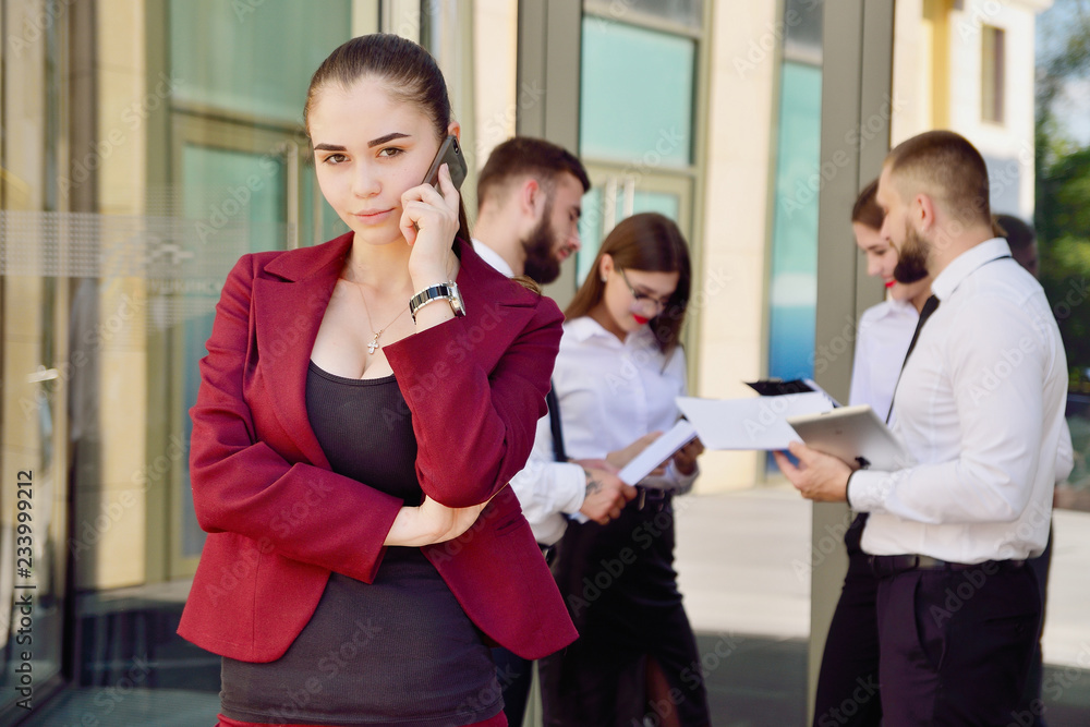 Girl talking on mobile phone. Young team of office workers. Girl in glasses. Business lady Girl talking on mobile phone. Young team of office workers. Girl in glasses. Business lady