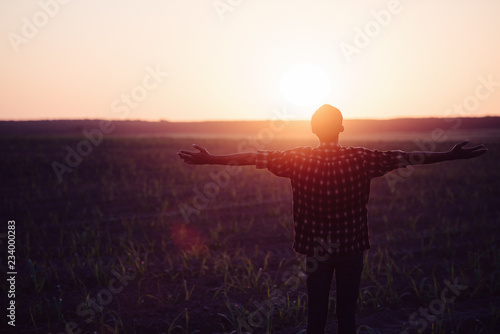 Feel good freedom concept. Happy young asian man enjoying freedom with open hands in farm and sunset sky background.