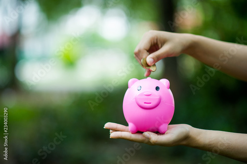 Female hand holding pink piggy bank, piggy bank and happy with savings. And copy space