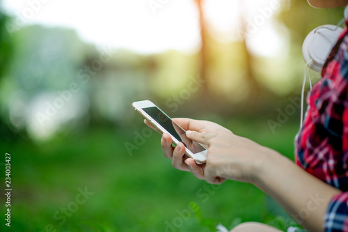 Girl playing phone on hand for online communication and contact Wear red shirt and green background And there is a copy space.