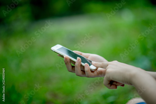 Girl playing phone on hand for online communication and contact Wear red shirt and green background And there is a copy space.
