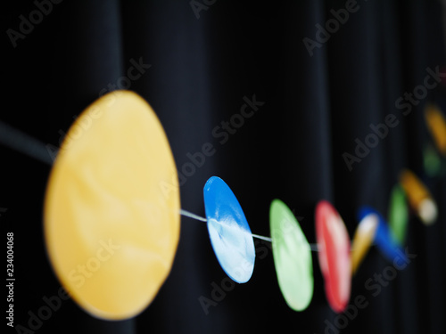 Red, yellow, blue and green decorative bunting in front of black curtain