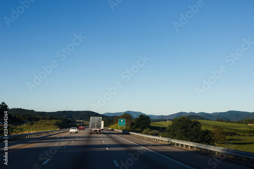 Cars and trucks drive along a beautiful scenic highway among mountains and hills on a sunny summer day. North Carolina / USA - July 8, 2018