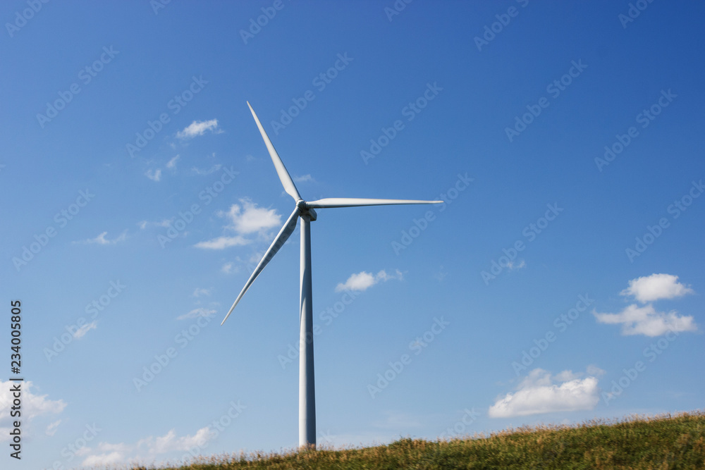 In the field there is a wind generator against the blue sky. Wind power.