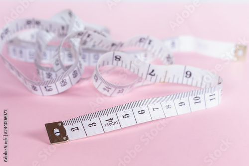 measure tape tool of sewing work on pink background.