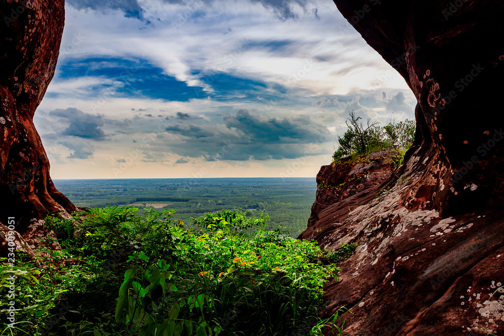 Looking out off a mountain from inside a vegitation filled cave at Phu Sing, Thailand