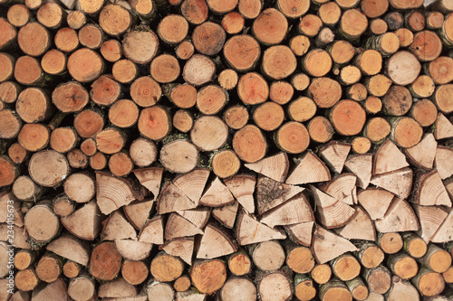 A woodpile of round logs and wood chucks in the countryside.