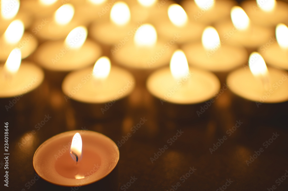 Round tea light candles burning in darkness. Advent or memorial prayer candle flame.