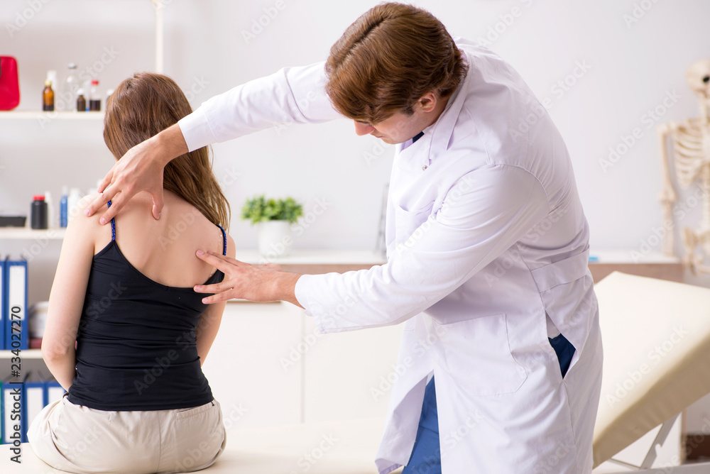 Obraz premium Female patient visiting young handsome doctor chiropractor 