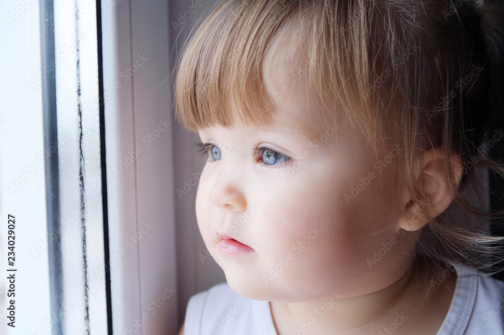 little child looking out window. baby girl longing to walk outdoors at rainy weather. little child looking out window. baby girl longing to walk outdoors at rainy weather.