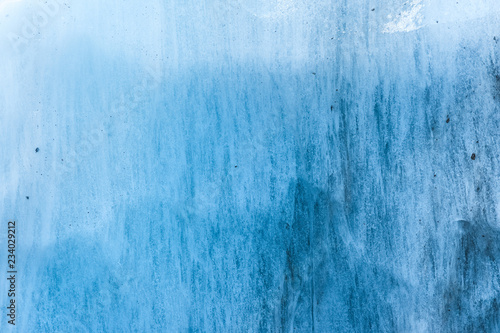 Close-up wall of a centuries-old glacier with a structure of stripes and bubbles. Ice blue light texture