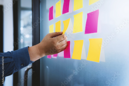 Close up hand of business man putting sticky post it note paper for share idea on meeting.