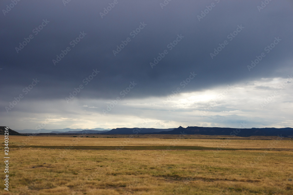 Summer day, dark sky, big dark blue clouds in the sky. In the steppe before the rain. Dark blue mountains on the horizon Summer day, dark sky, big dark blue clouds in the sky. In the steppe before the rain. Dark blue mountains on the horizon