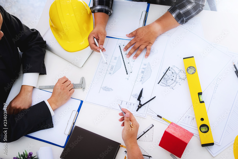 engineer people meeting working and pointing at a drawings in office for discussing. Engineering tools and construction concept. engineer people meeting working and pointing at a drawings in office for discussing. Engineering tools and construction concept.
