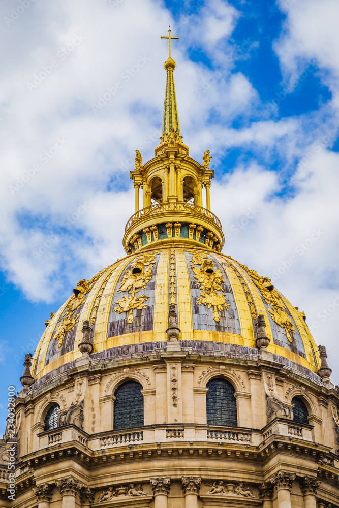 Golden dome of the hotel des Invalides, under which rests the tomb of Napoleon Bonaparte in Paris France on a summer day under a blue sky with white clouds
