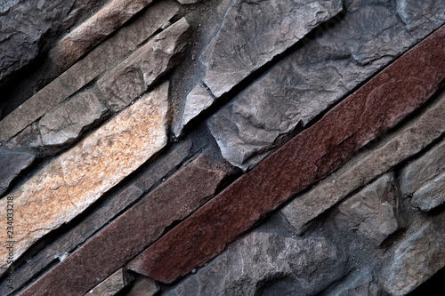 Stone wall of natural stones in different sizes and different colors. Rustic stone veneer in shades of brown color. Wall covering with natural stones