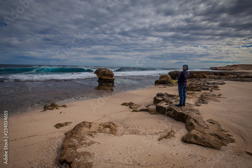 Women looking out towards masive waves breaking at Surf Point on Dirk Hartog island, Western Australia