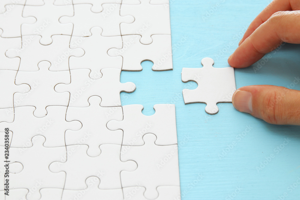 male hand putting the last piece in the puzzle. male hand putting the last piece in the puzzle.