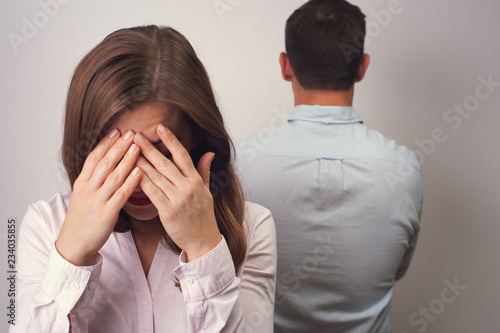 Woman dressed in white blouse closing her face with hands standing with their backs turned to each other. Silent scene coupe quarrelling going through rough times photo