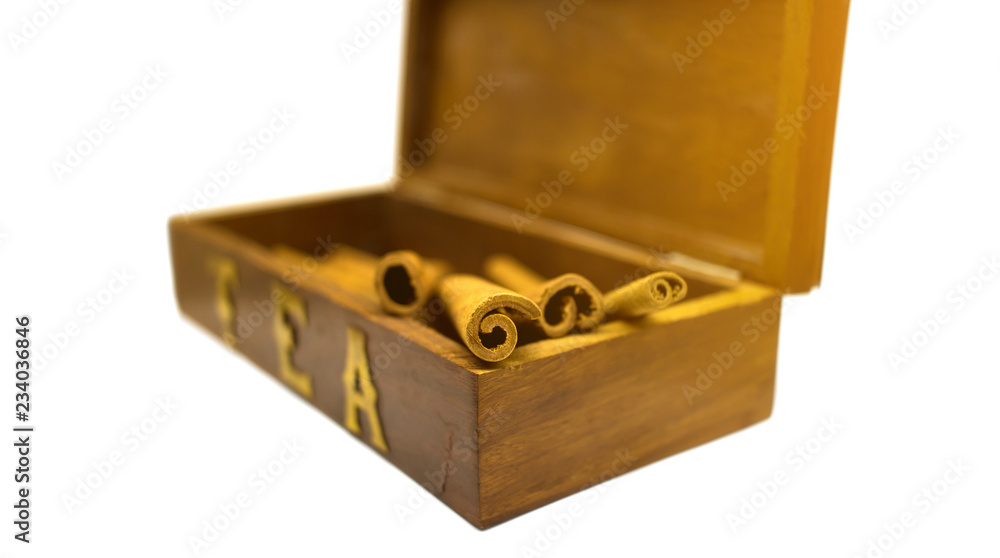 Cinnamon sticks in tea box isolated on white background. Sun beam toned