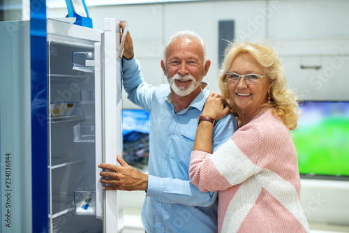 Caucasian senior couple buying new fridge. Tech store interior.