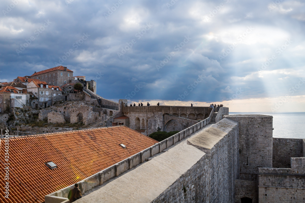 Sunrays shining out of the dramatic cloudscape over walkway up to the fortress of Durbrovnik, Croatia