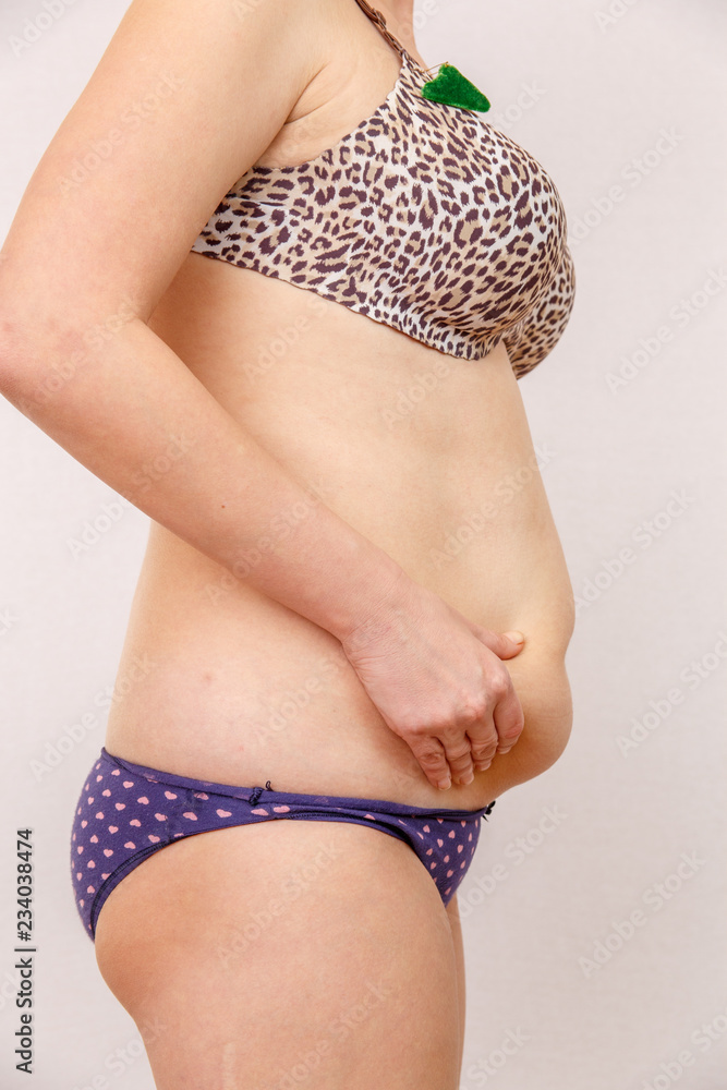 A 30-year-old woman with overweight shows her body, legs, stomach, breasts  in lingerie on a light isolated background. Concept to demonstrate body  changes from alcohol abuse and over-eating Photos