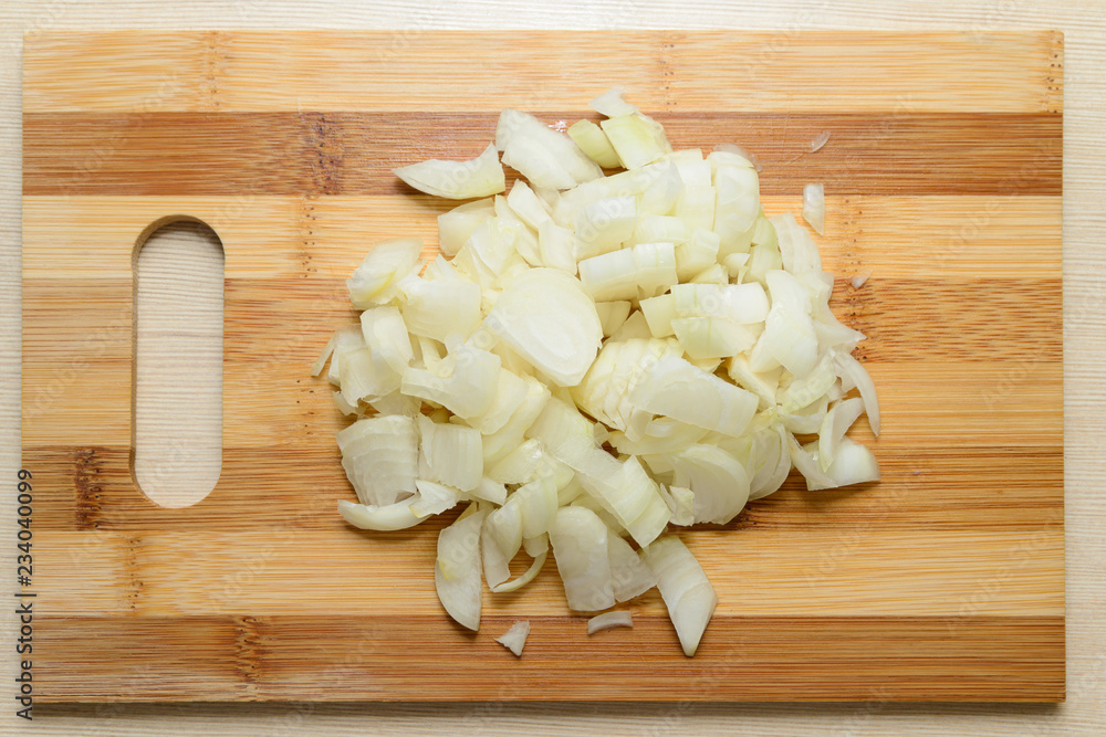 crumbled heap of white onions on a wooden board