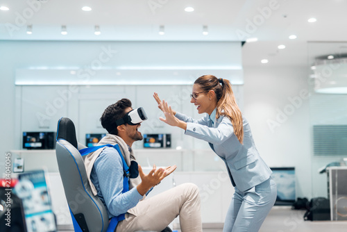 Happy multicultural couple trying out virtual reality technology. Tech store interior.