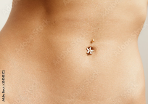 Young woman navel with jewelry - piercing on the umbilicus. photo