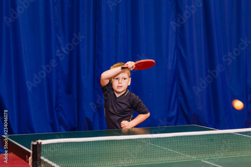a child in the gym playing table tennis, hitting the ball in table tennis