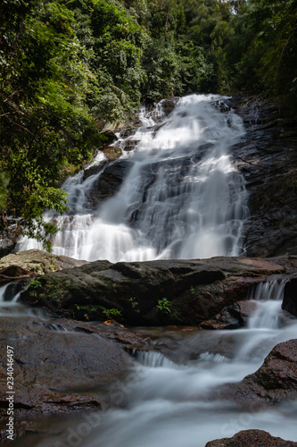 Long exposure of a picturesque waterfall flowing through a tropical rainforest photo