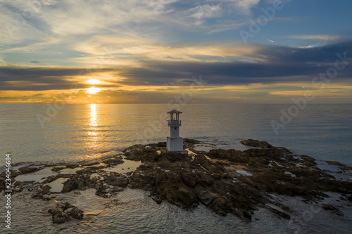 Aerial drone view of a lighthouse and beautiful tropical sunset over the ocean