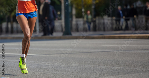 Running in the city roads. Young woman runner, front view, banner, blur background © Rawf8